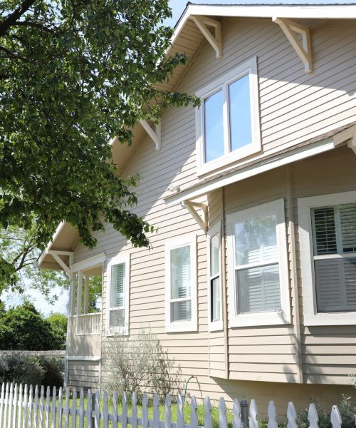 New Siding Repair on two story house with a white picket fence